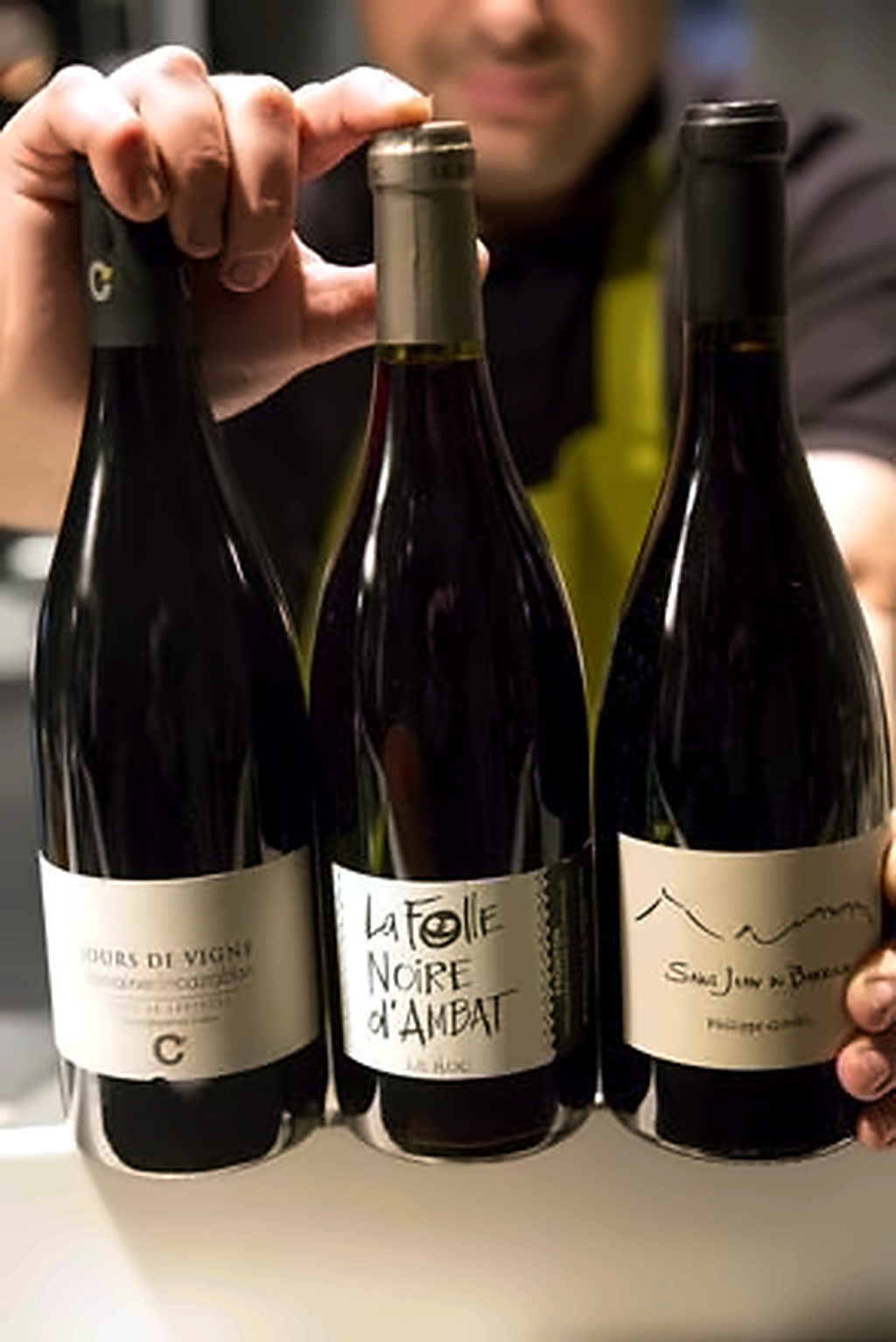 Archive 2014 : trois bouteilles de vin tenues à la main dans la salle