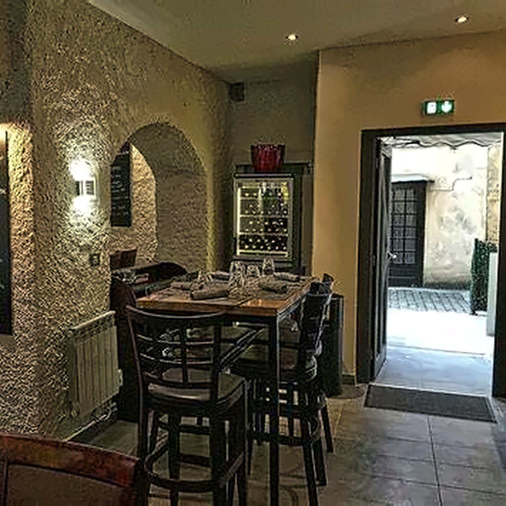 Petite salle voûtée en pierre, table dressée et cave à vin