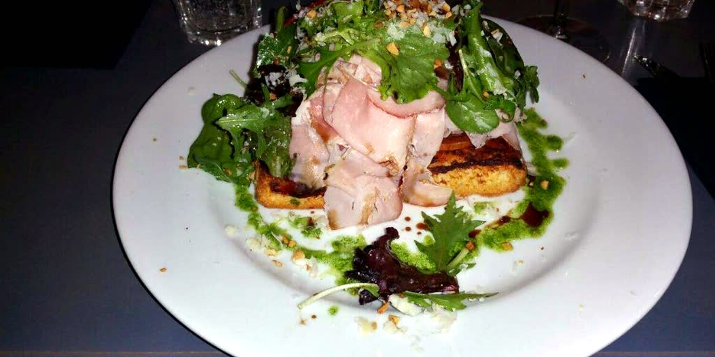 Tartine italienne garnie de charcuterie, roquette et éclats de noisette